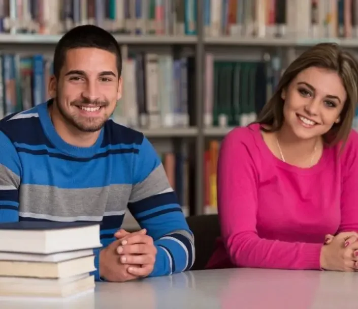 A man and woman sitting at a table with books