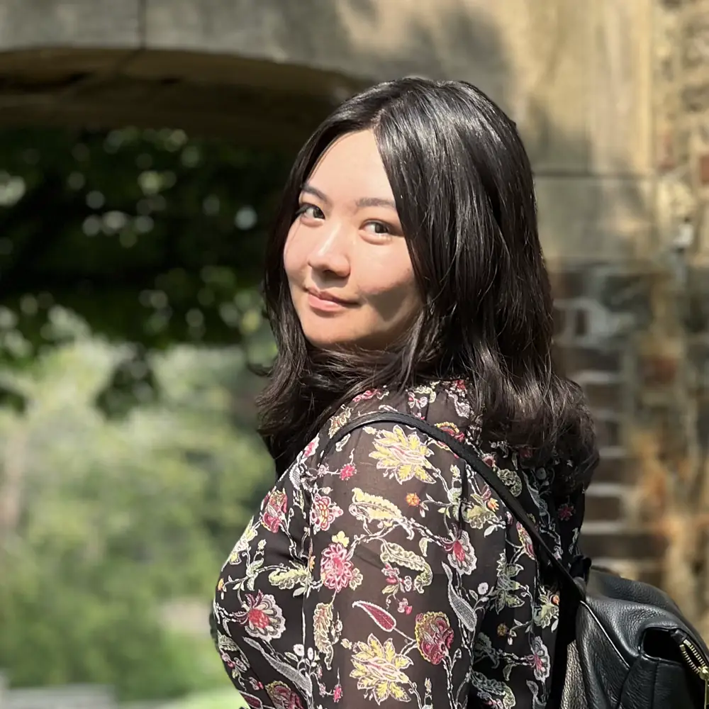 Stephanie Wang, Northside Tutoring tutor, smiling outdoors beside a stone archway.